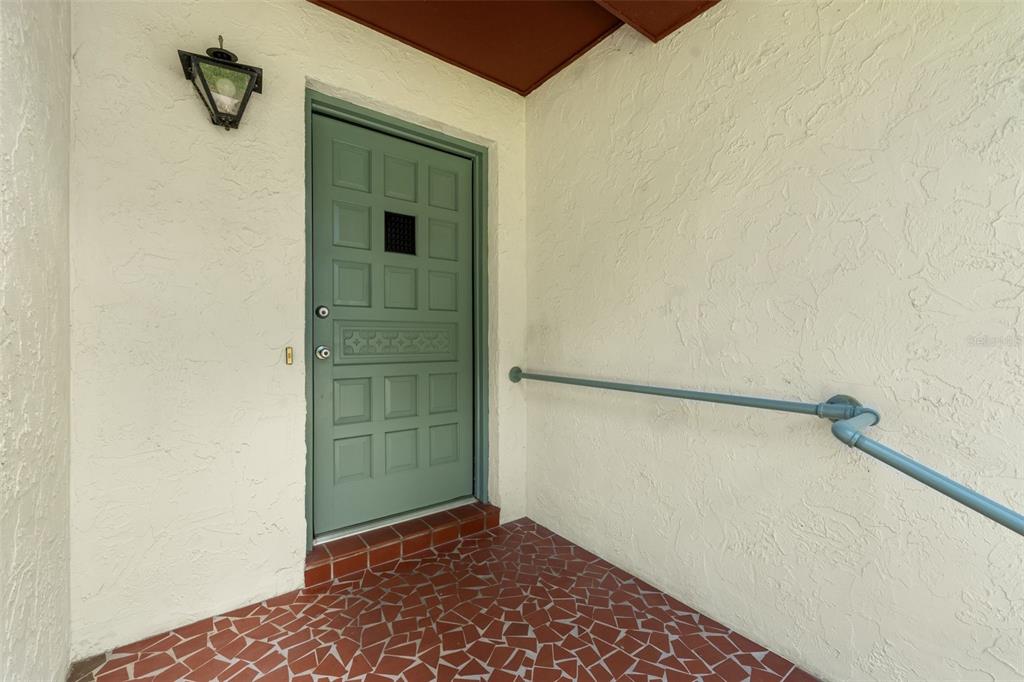 A green front door with a small window sits on a tiled porch with a railing — 2413 NW 63RD TERRACE, GAINESVILLE, FL
