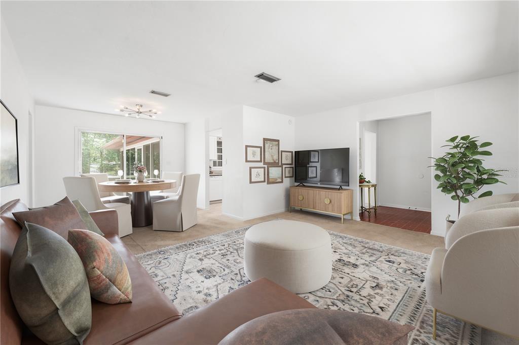A living room with a brown leather sofa, round ottoman, dining area, and television console — 2413 NW 63RD TERRACE, GAINESVILLE, FL