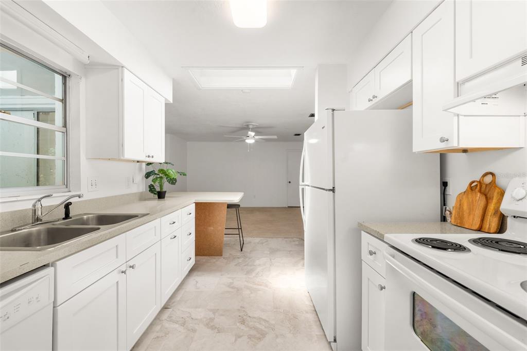 A white kitchen features light countertops, a double sink, and a breakfast bar — 2413 NW 63RD TERRACE, GAINESVILLE, FL