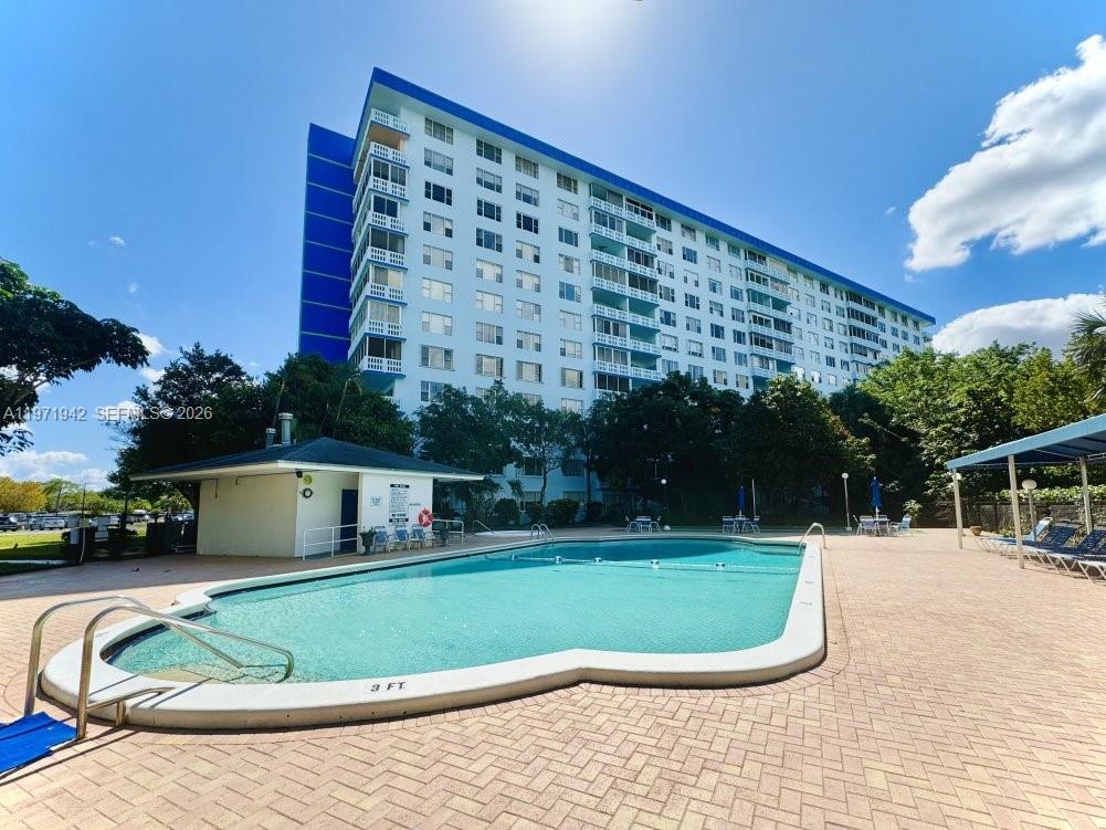 A large apartment building stands behind a swimming pool with a brick patio — 4001 Hillcrest Dr # 909, Hollywood FL 33021, HOLLYWOOD, FL