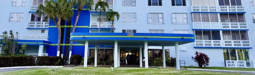 The exterior of a multi-story blue apartment building features a covered entrance and palm trees — 4001 Hillcrest Dr # 909, Hollywood FL 33021, HOLLYWOOD, FL