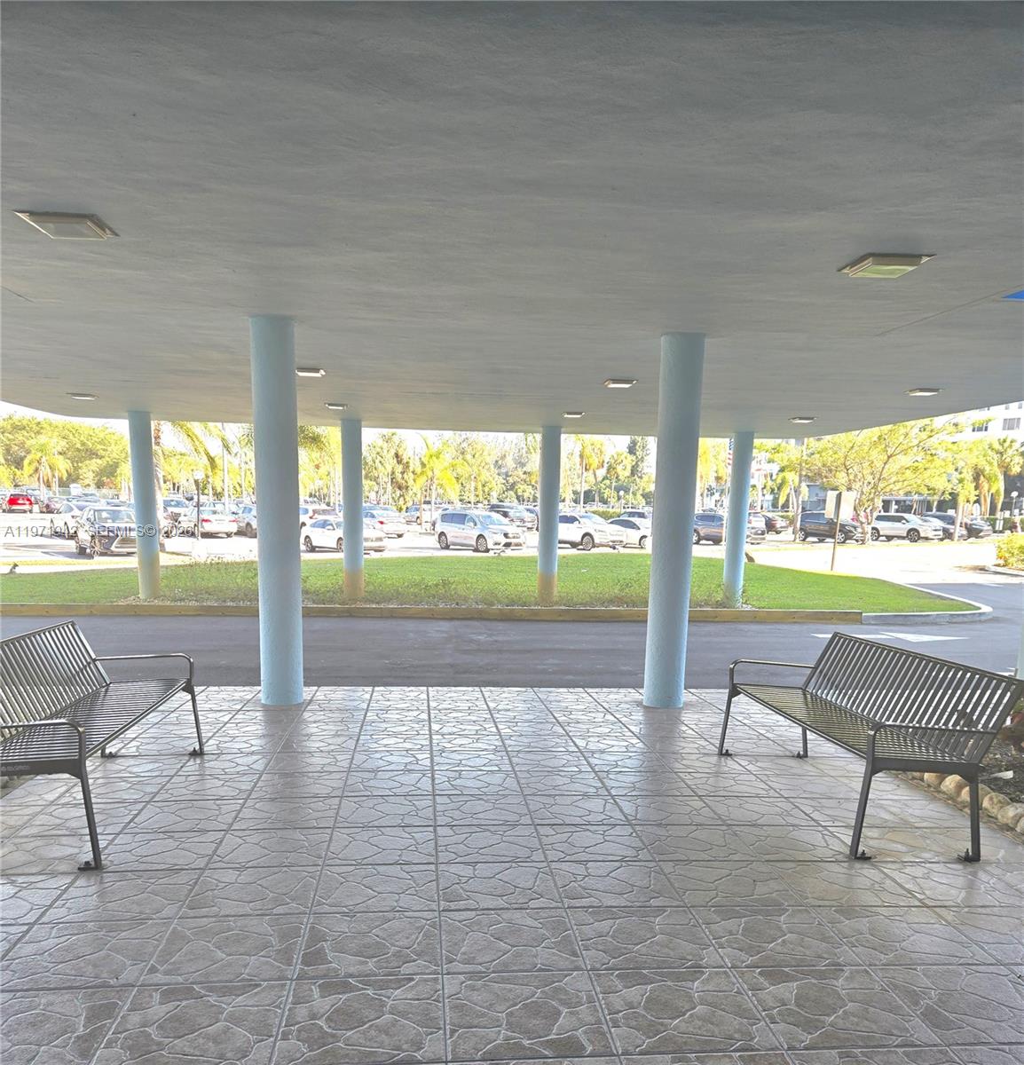 A covered outdoor entryway features two metal benches on a tiled floor with support columns — 4001 Hillcrest Dr # 909, Hollywood FL 33021, HOLLYWOOD, FL