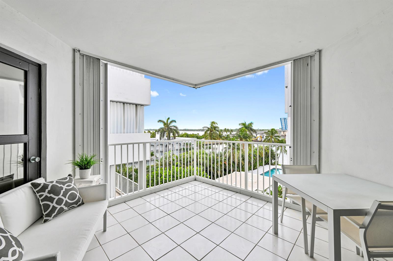 A balcony with white tile floors, a white sofa, and a dining set overlooking palm trees — 2860 S Ocean Boulevard # 511, Palm Beach FL 33480, PALM BEACH, FL