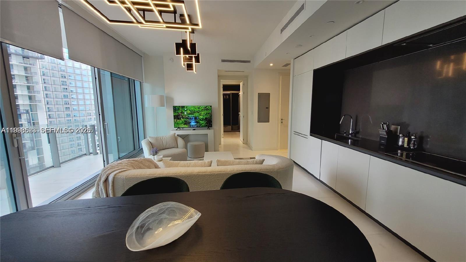 A modern open-concept living area features a kitchen, dining table, and floor-to-ceiling windows — 300 Biscayne Blvd Way # 2908, Miami FL 33131, MIAMI, FL
