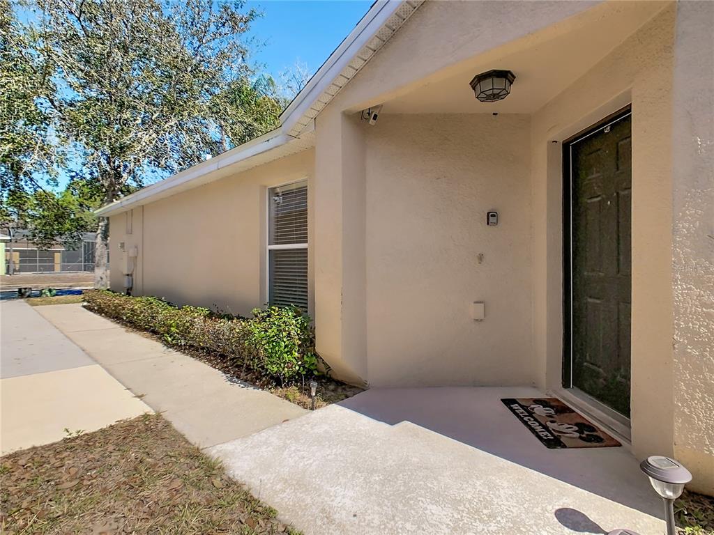 A tan stucco house exterior features a front entryway, a window, and a concrete walkway — 1958 ROYAL RIDGE DRIVE, DAVENPORT, FL