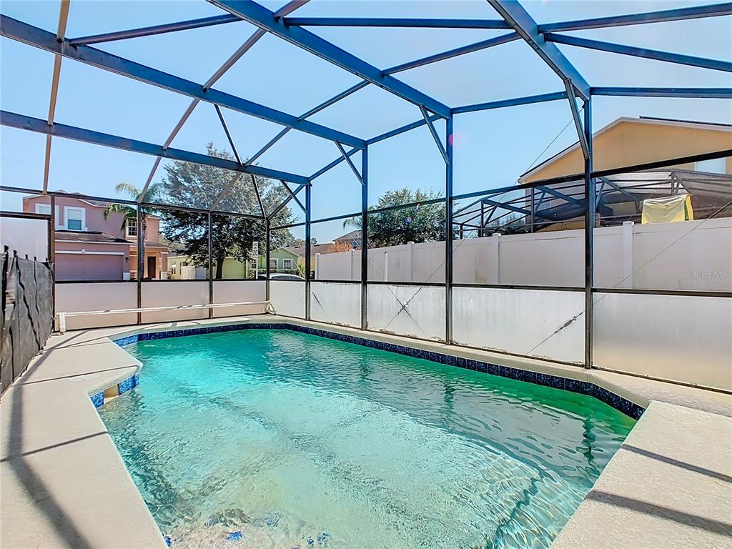 A swimming pool enclosed by a metal-framed screen structure in a residential backyard — 1958 ROYAL RIDGE DRIVE, DAVENPORT, FL