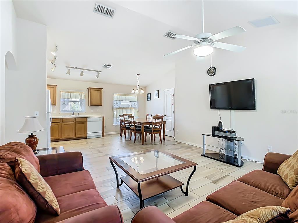 An open-concept living and dining area features tile flooring, a ceiling fan, and wooden cabinetry — 1958 ROYAL RIDGE DRIVE, DAVENPORT, FL