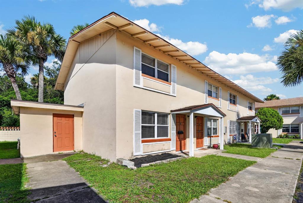 A two-story apartment building with beige stucco walls, brown doors, and a concrete walkway — 1600 S PALMETTO AVENUE UNIT 111, SOUTH DAYTONA, FL