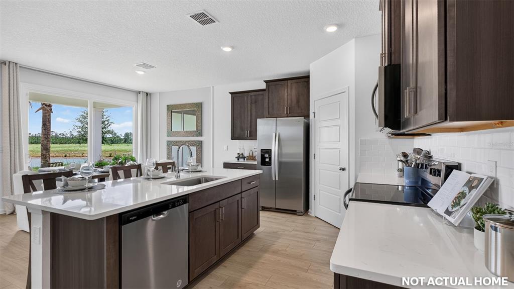 This kitchen features dark wood cabinets, white quartz countertops, stainless steel appliances, and tile flooring — 155 SPRINGWOOD DRIVE, PALM COAST, FL