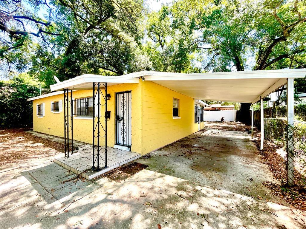 A yellow single-story house with a concrete carport and a small front porch — 1003 E 22ND AVENUE, TAMPA, FL