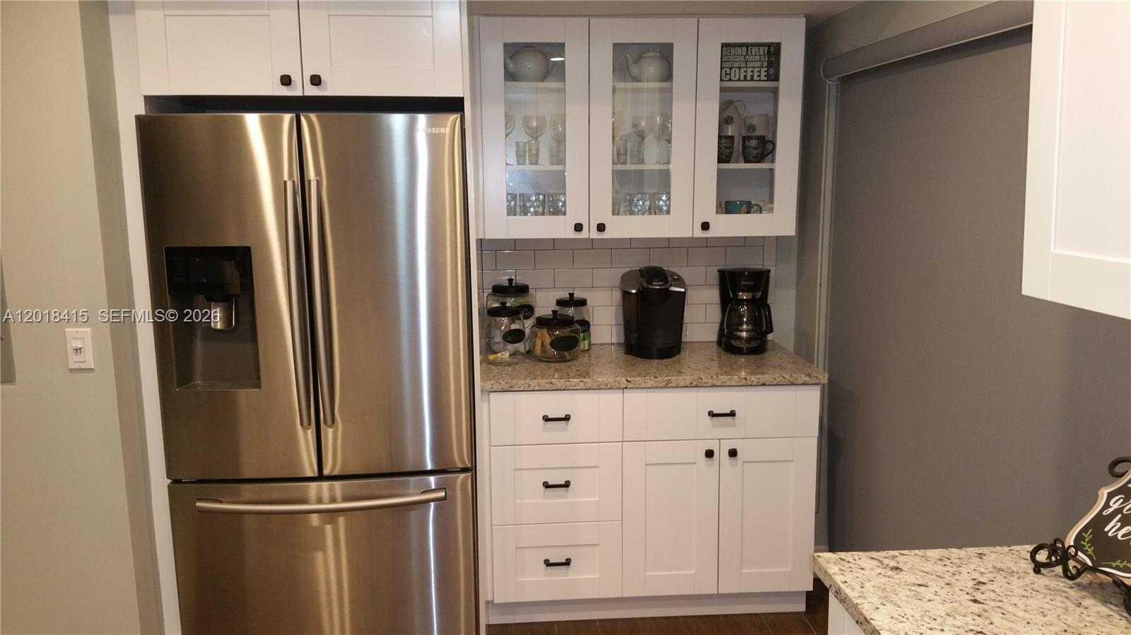 A kitchen features a stainless steel refrigerator, white cabinetry, and a granite countertop coffee station — 11325 SW 133rd Ct # 3, Miami FL 33186, MIAMI, FL