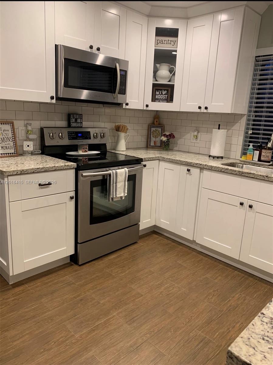 A kitchen features white shaker cabinets, stainless steel appliances, granite countertops, and a subway tile backsplash — 11325 SW 133rd Ct # 3, Miami FL 33186, MIAMI, FL