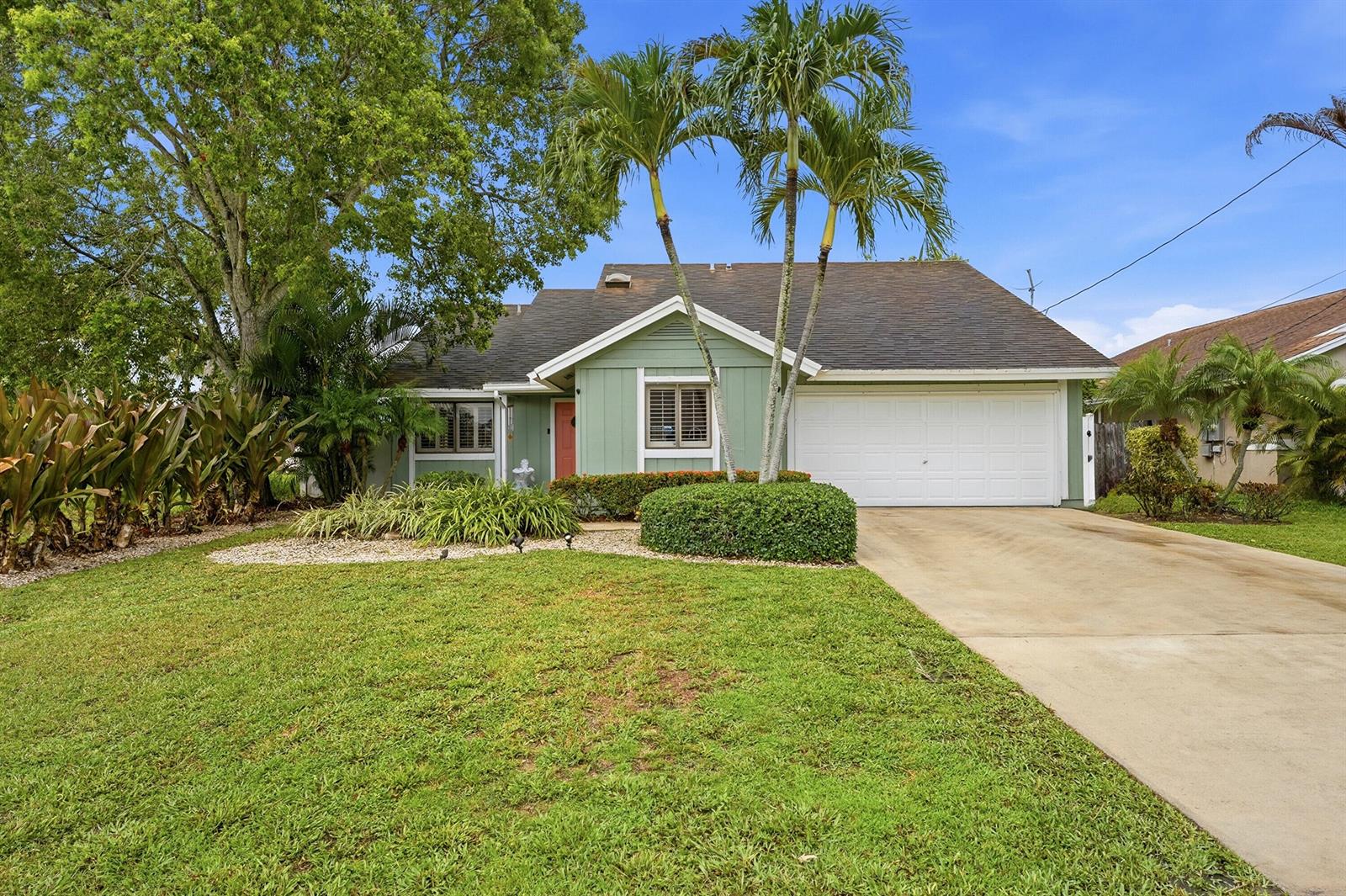 A single-story house with green siding, a white garage door, and two tall palm trees — 6273 Barbara Street, Jupiter FL 33458, JUPITER, FL