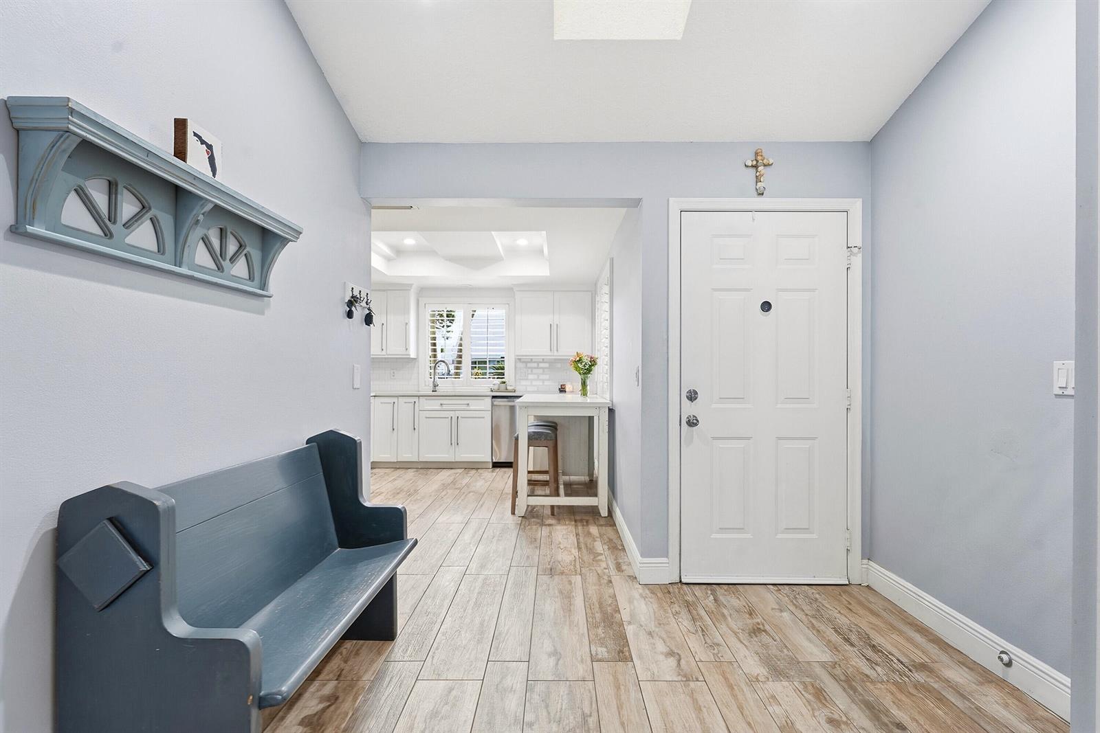 An entryway with a blue bench and shelf leads into a white kitchen — 6273 Barbara Street, Jupiter FL 33458, JUPITER, FL