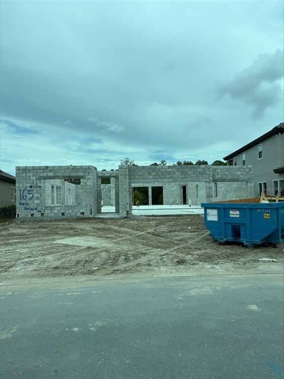 A residential construction site shows a concrete block structure with open wall frames and a dumpster — 8842 EASTWYCK DRIVE, PARRISH, FL