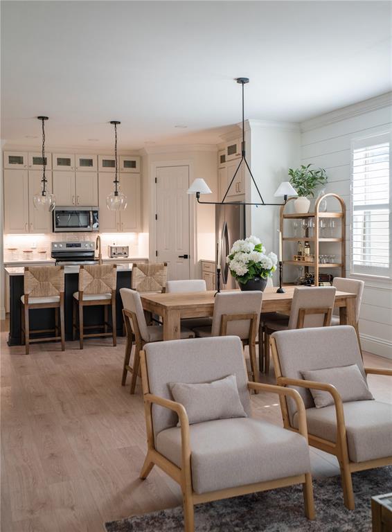 An open-concept kitchen and dining area features light wood floors, white cabinetry, and neutral furniture — 325 VILLORESI BOULEVARD, NOKOMIS, FL