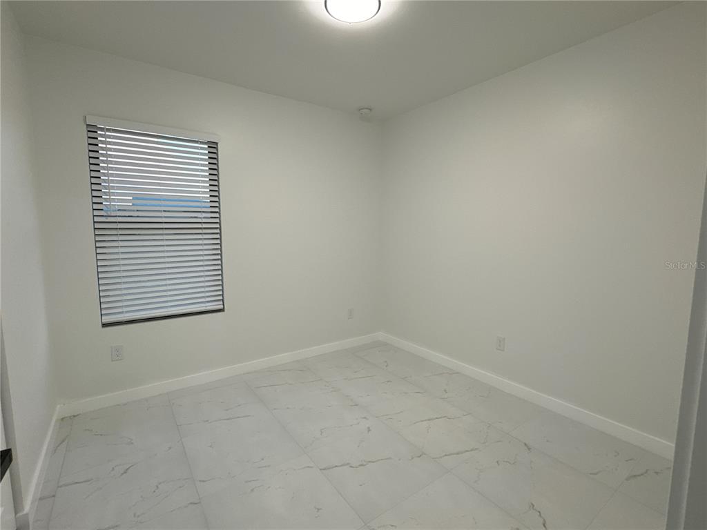 An empty room features white walls, a single window with blinds, and light-colored tile flooring — 1775 GLENWAY COURT, FORT MYERS, FL