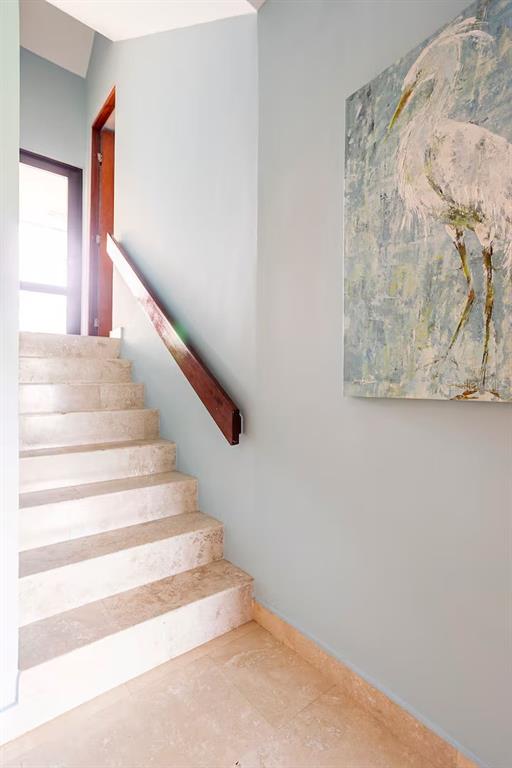 A staircase with light stone steps and a dark wood handrail leads to a doorway — 166 BEACH VILLAGE, HUMACAO, PR