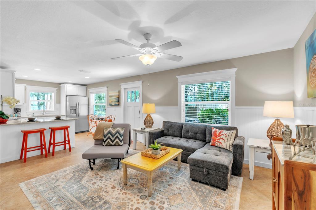 An open-concept living room and kitchen featuring a gray sectional, area rug, and bar stools — 205 PEACOCK LANE UNIT A, HOLMES BEACH, FL