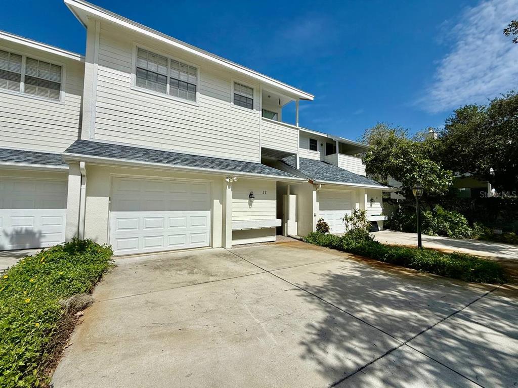 A two-story townhouse with white siding, two garage doors, and a concrete driveway — 5220 S RUSSELL STREET UNIT 32, TAMPA, FL