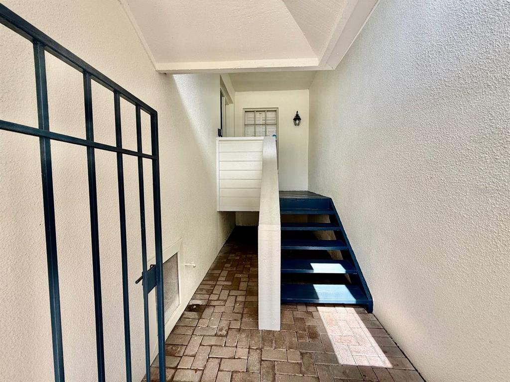 A brick-paved entryway features a dark metal gate and a set of blue wooden stairs — 5220 S RUSSELL STREET UNIT 32, TAMPA, FL