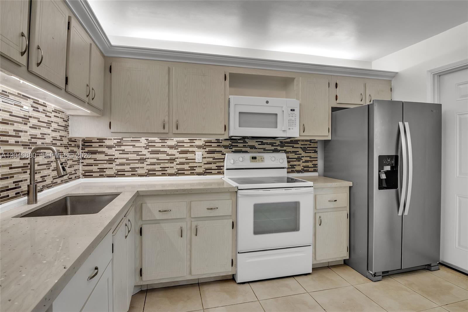A kitchen features light wood cabinets, a white stove, a stainless steel refrigerator, and backsplash — 1000 NE 14th Ave # 503, Hallandale Beach FL 33009, HALLANDALE BEACH, FL