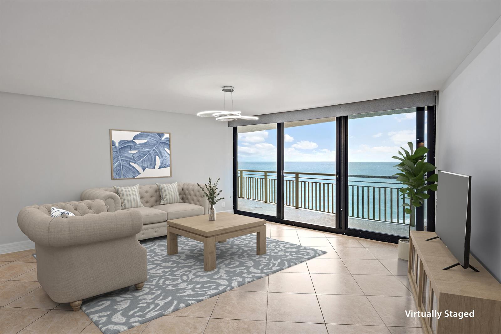 This virtually staged living room features tile flooring, a beige sofa, and a balcony view — 3000 N Ocean Drive # 17d, Riviera Beach FL 33404, RIVIERA BEACH, FL