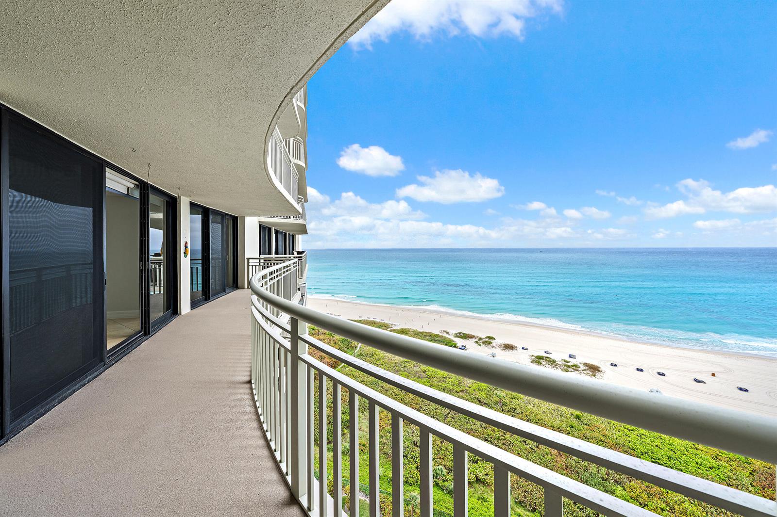 A curved balcony overlooks a sandy beach and the ocean under a blue sky — 3000 N Ocean Drive # 17d, Riviera Beach FL 33404, RIVIERA BEACH, FL