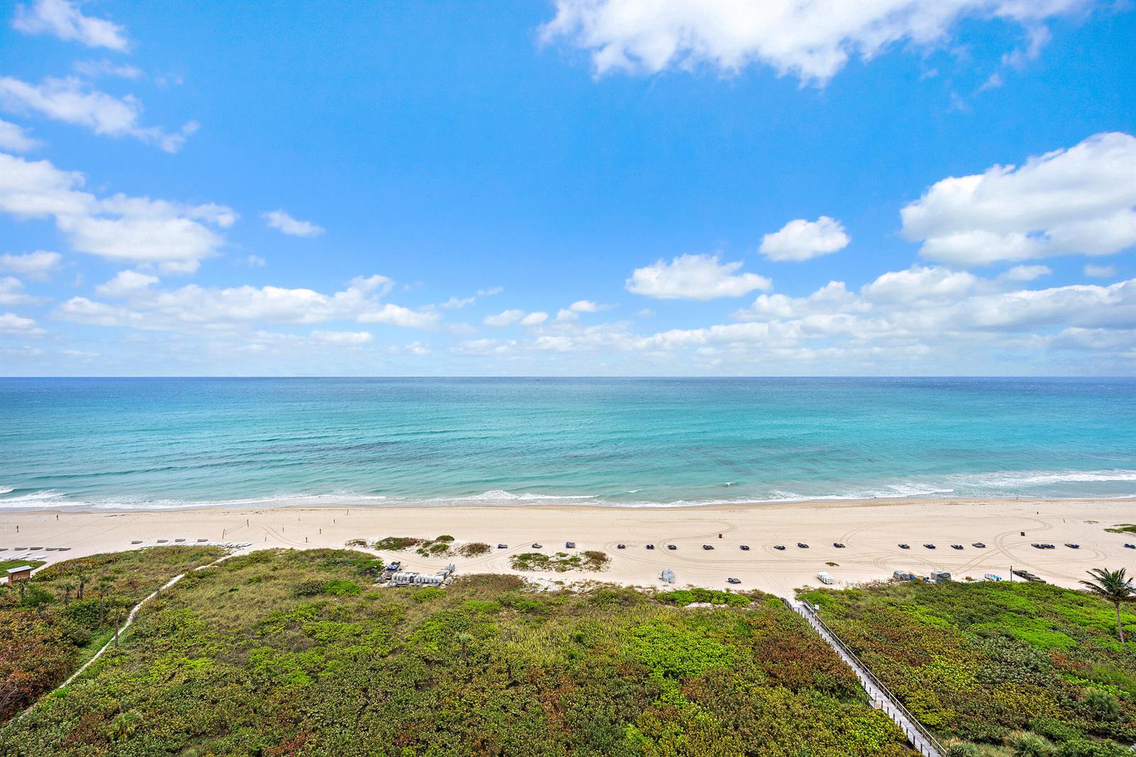 An elevated view of a sandy beach, turquoise ocean, and coastal vegetation under a blue sky — 3000 N Ocean Drive # 17d, Riviera Beach FL 33404, RIVIERA BEACH, FL