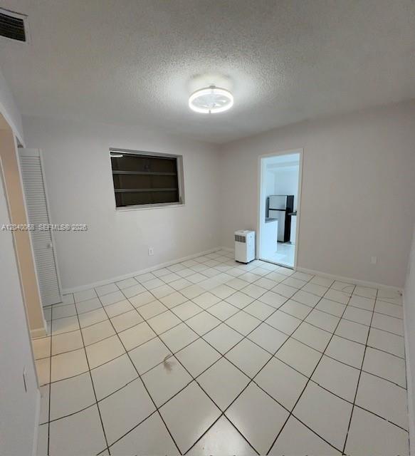 An empty room with white tile flooring, a ceiling light, and a portable air conditioner — 5641 SW 39th St, West Park FL 33023, WEST PARK, FL