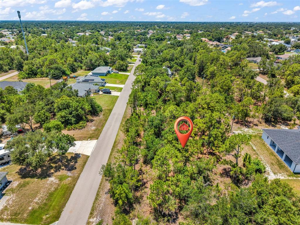 An aerial view shows a vacant, wooded residential lot marked with a red location pin — 325 WYLER STREET, PORT CHARLOTTE, FL