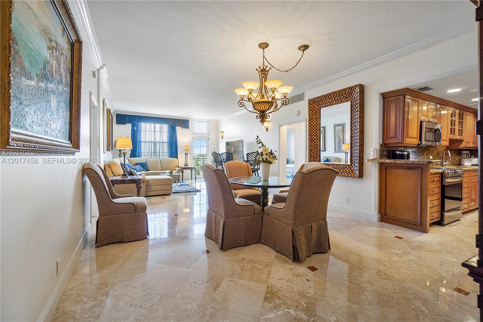 A dining area and living room with marble floors, a chandelier, and wooden kitchen cabinets — 2851 S Ocean Blvd # 7U, Boca Raton FL 33432, BOCA RATON, FL