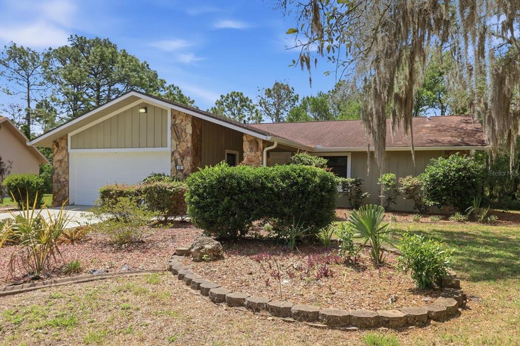 A single-story house with a stone facade, garage, and landscaped front yard under a blue sky — 20 SALVIA COURT, HOMOSASSA, FL