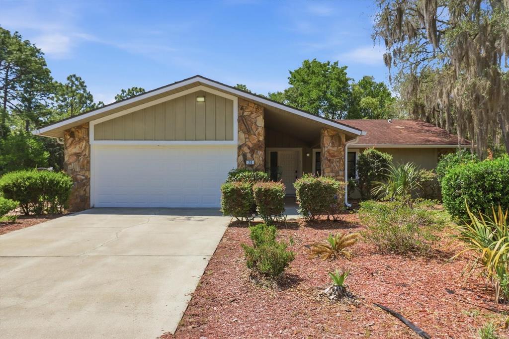 A single-story house with a white garage door, stone accents, and a concrete driveway — 20 SALVIA COURT, HOMOSASSA, FL