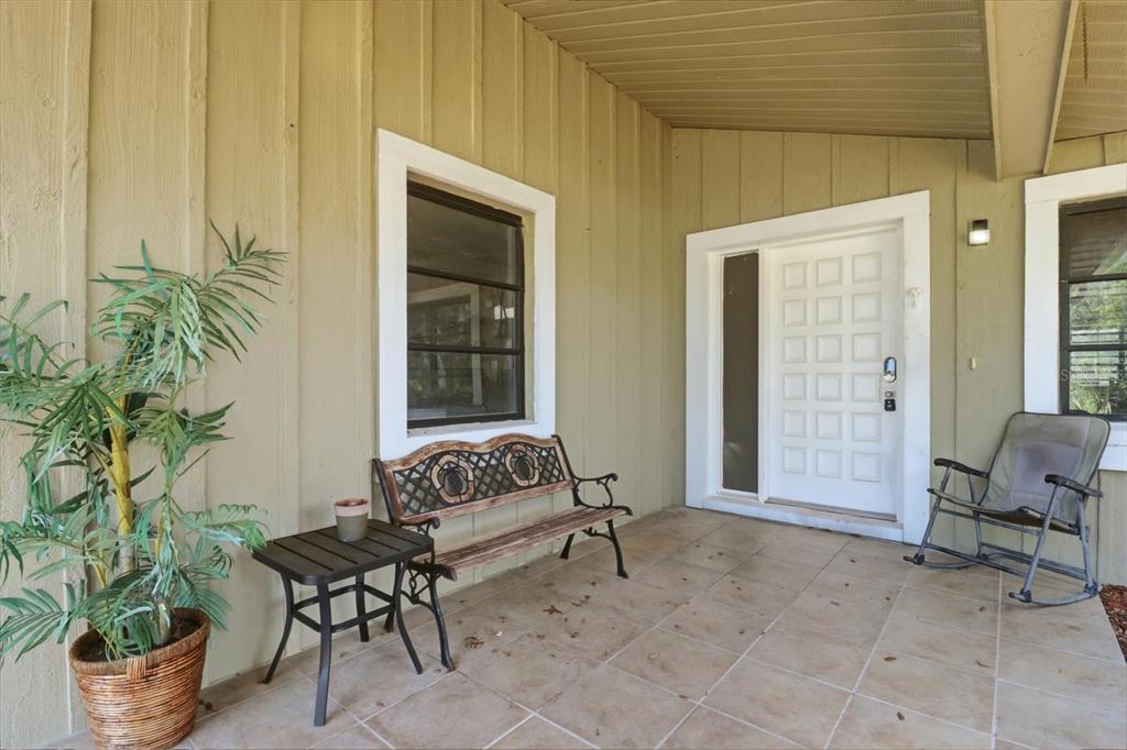 A covered front porch features tiled flooring, a wooden bench, a rocking chair, and siding — 20 SALVIA COURT, HOMOSASSA, FL
