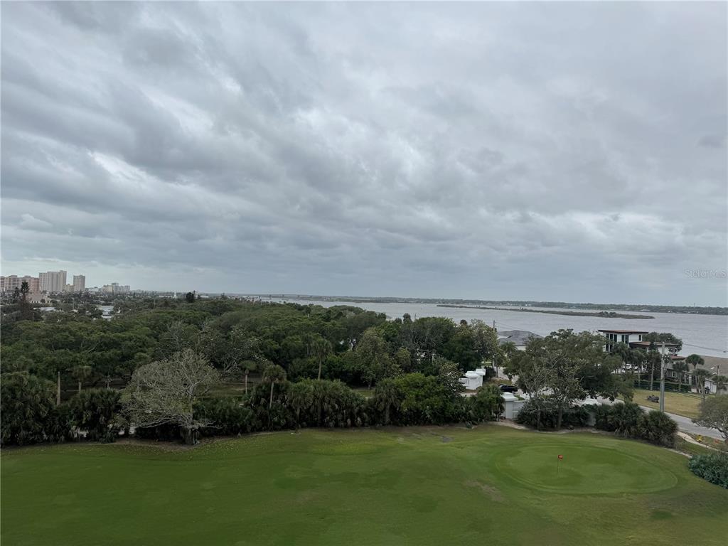 An elevated view shows a golf course green, dense trees, and a body of water — 1 OCEANS WEST BOULEVARD UNIT 6B1, DAYTONA BEACH, FL