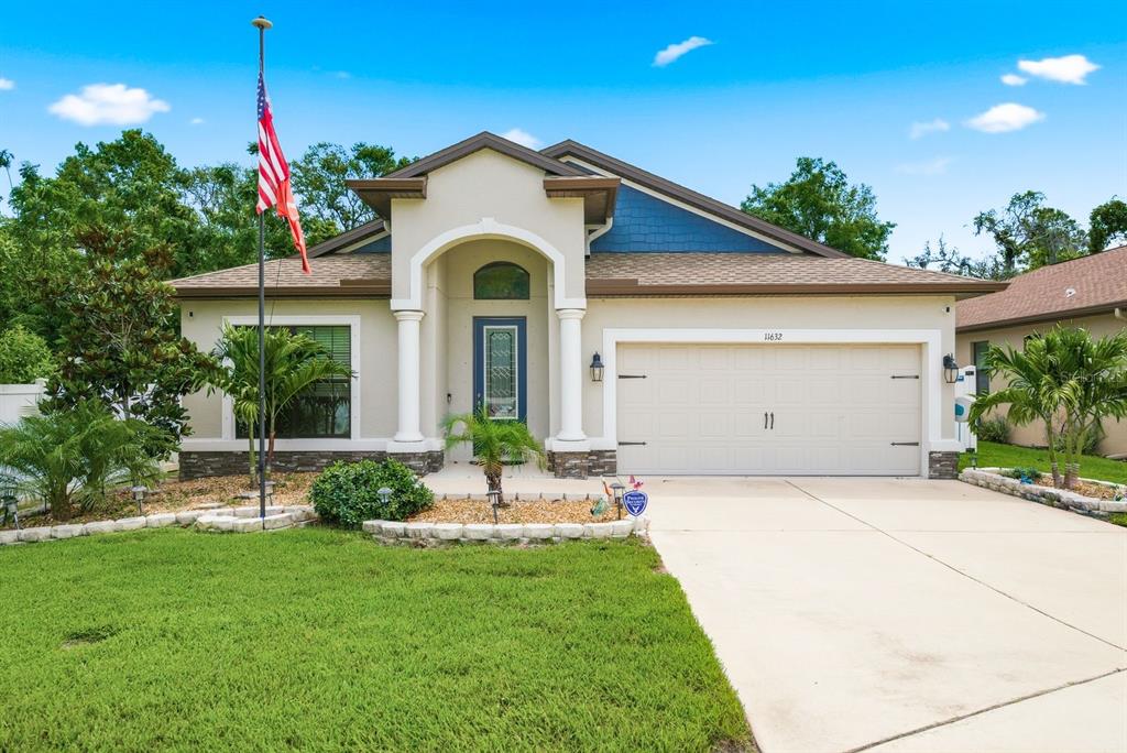 A single-story house with a beige stucco exterior, a two-car garage, and a front porch — 11632 WEAVER HOLLOW ROAD, NEW PORT RICHEY, FL