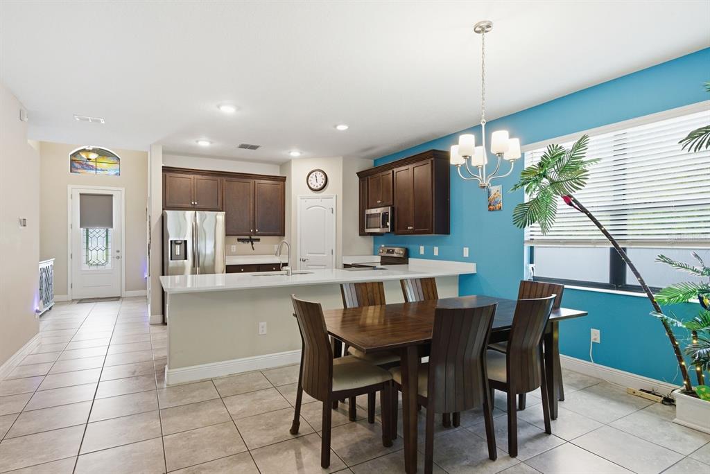 A kitchen and dining area with dark wood cabinets, white countertops, and a blue wall — 11632 WEAVER HOLLOW ROAD, NEW PORT RICHEY, FL