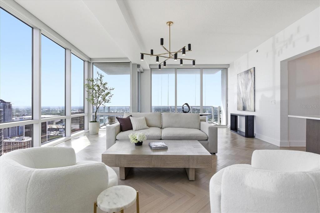 A modern living room features a light-colored sofa, two armchairs, and floor-to-ceiling windows — 150 E ROBINSON STREET UNIT 30C-2, ORLANDO, FL