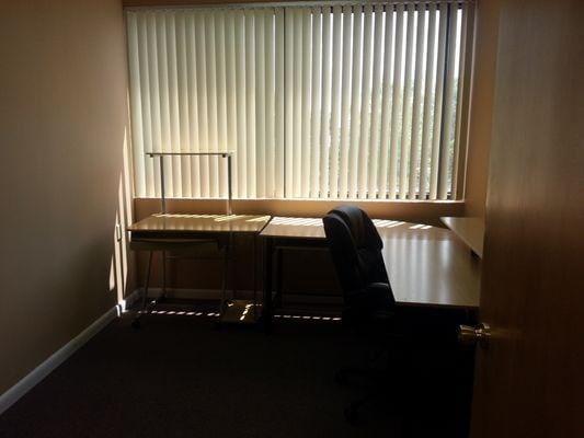 A small office features a desk, an office chair, and vertical blinds covering a large window — 10001 Oakland Park Boulevard # 302, Sunrise FL 33351, SUNRISE, FL