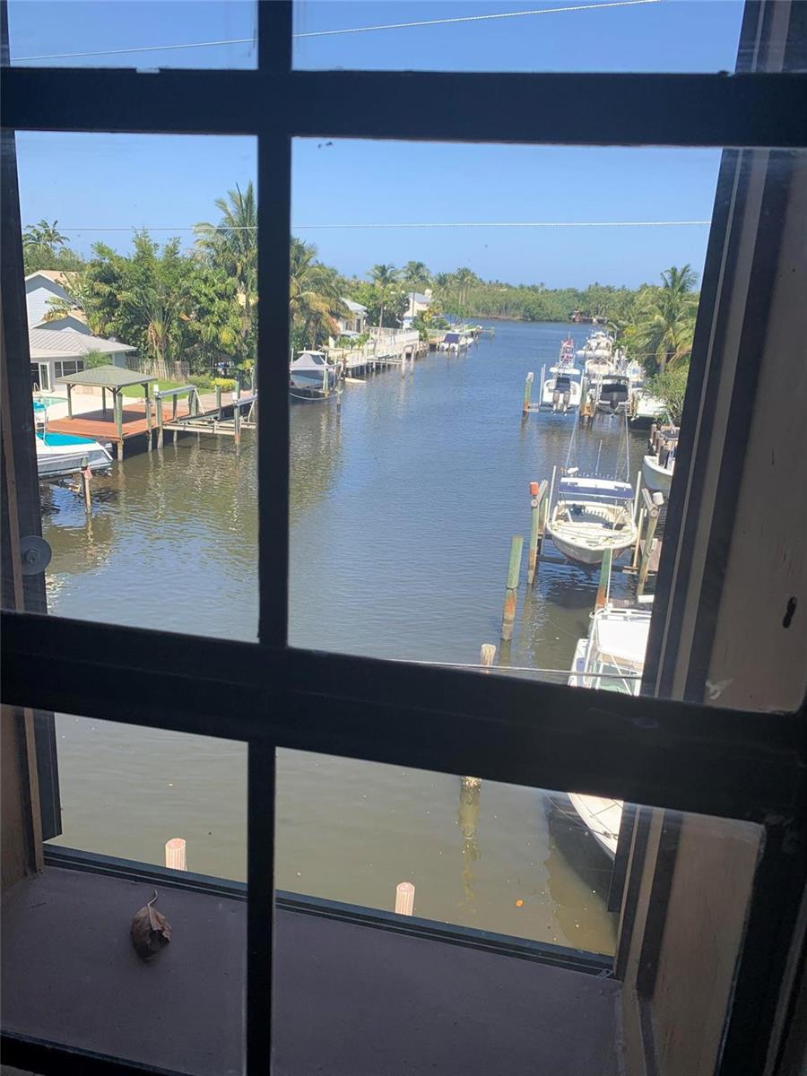 A view through a window shows a canal lined with docks, boats, and palm trees — 1200 S Federal Highway, Boynton Beach FL 33435, BOYNTON BEACH, FL