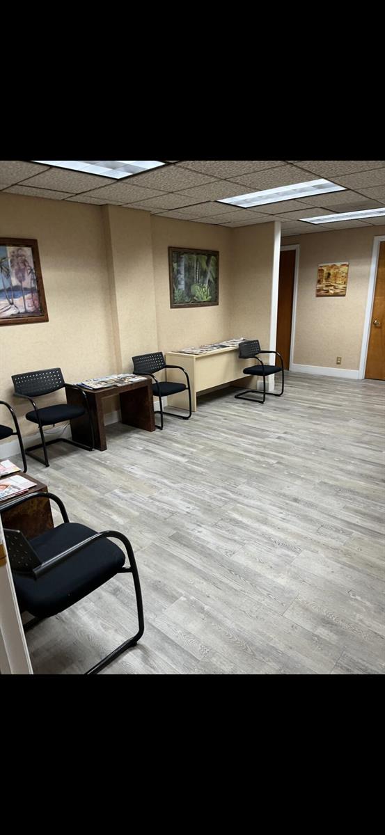 A waiting room features light wood-look flooring, beige walls, black chairs, and framed artwork — 1200 S Federal Highway, Boynton Beach FL 33435, BOYNTON BEACH, FL