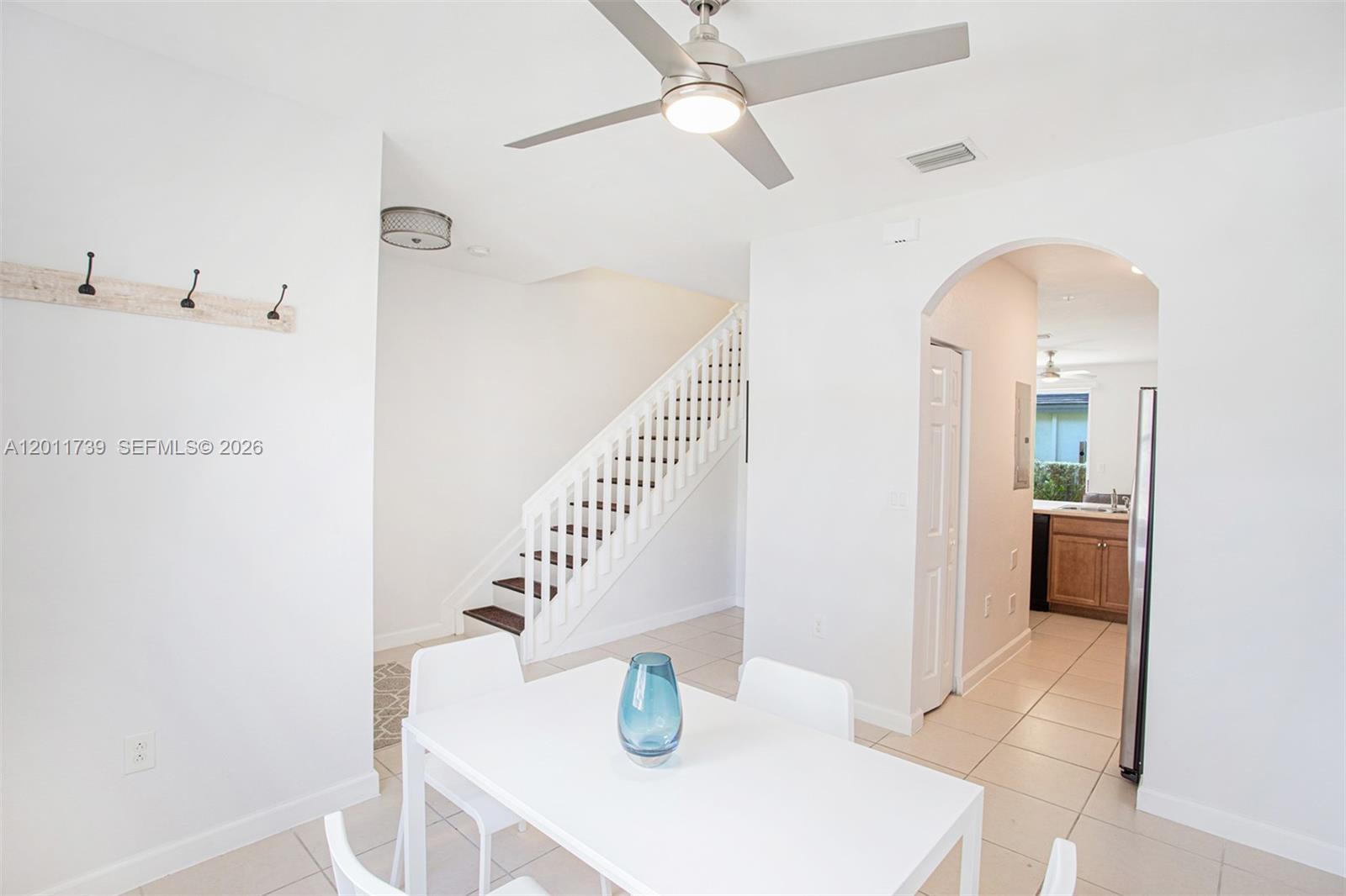 A dining area features a white table, a ceiling fan, and a staircase nearby — 132 SE 28th Pl # 7, Homestead FL 33033, HOMESTEAD, FL