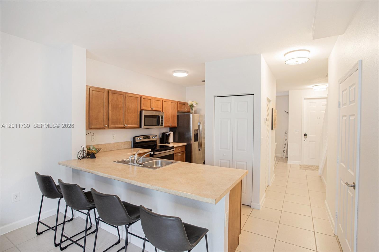 A kitchen features wood cabinets, stainless steel appliances, a breakfast bar, and tile flooring — 132 SE 28th Pl # 7, Homestead FL 33033, HOMESTEAD, FL