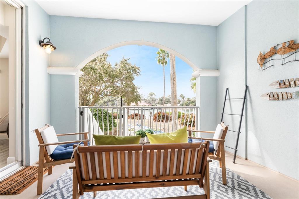 A covered balcony features a wooden bench, two chairs, and a view of a lake — 102 YACHT HARBOR DRIVE UNIT 176, PALM COAST, FL