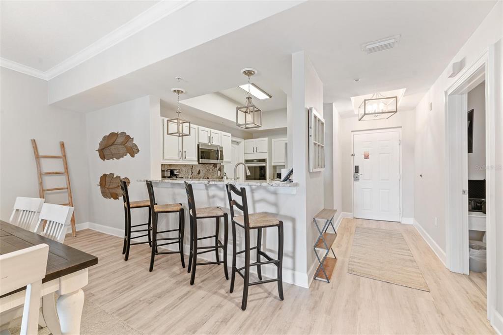 A kitchen with white cabinets and a breakfast bar overlooks a dining area and entryway — 102 YACHT HARBOR DRIVE UNIT 176, PALM COAST, FL