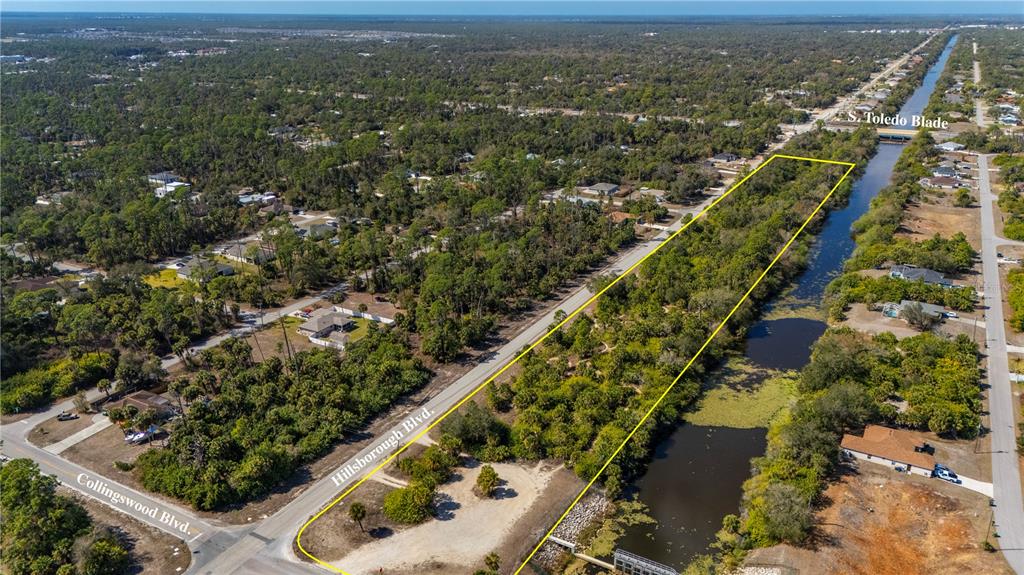 An aerial view shows a vacant, wooded lot bordered by a road and a canal — W HILLSBOROUGH BOULEVARD, NORTH PORT, FL
