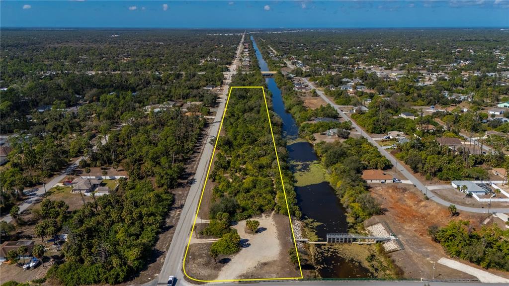 An aerial view shows a vacant, wooded lot bordered by a road and a canal — W HILLSBOROUGH BOULEVARD, NORTH PORT, FL