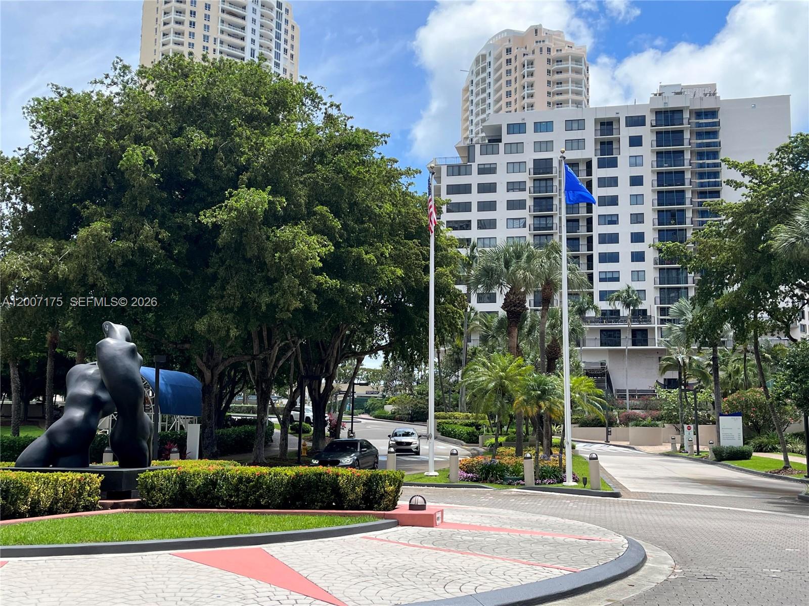 A large abstract sculpture sits in a landscaped roundabout in front of tall residential buildings — 540 Brickell Key Dr # 1809, Miami FL 33131, MIAMI, FL
