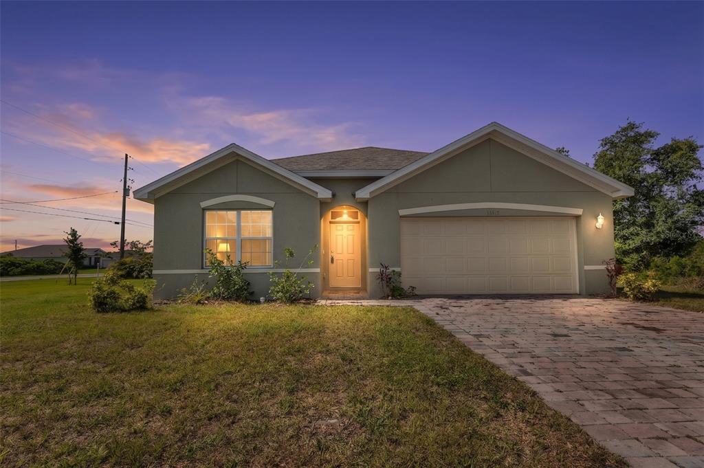 A single-story house with a beige stucco exterior, a two-car garage, and a paved driveway — 26567 DEEP CREEK BOULEVARD, PUNTA GORDA, FL